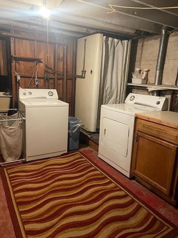 clothes washing area with cabinets and separate washer and dryer