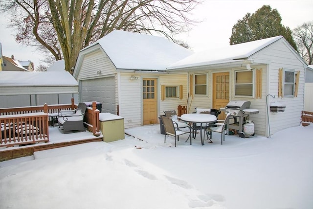 snow covered rear of property with a garage