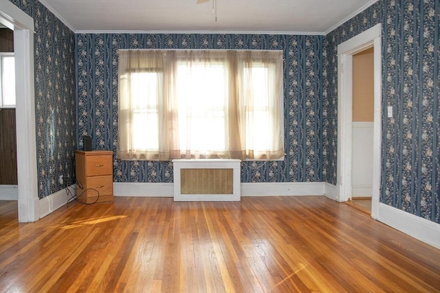 interior space featuring hardwood / wood-style floors, plenty of natural light, radiator, and ornamental molding