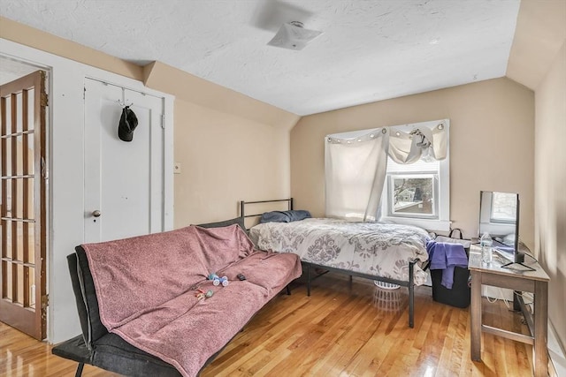 bedroom with vaulted ceiling, hardwood / wood-style floors, and a closet