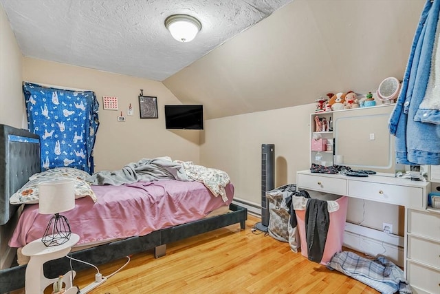 bedroom with hardwood / wood-style flooring, lofted ceiling, and a textured ceiling