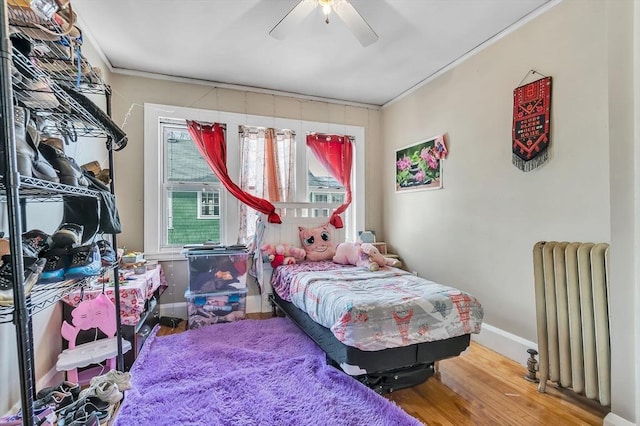 bedroom featuring hardwood / wood-style floors, crown molding, radiator heating unit, and ceiling fan