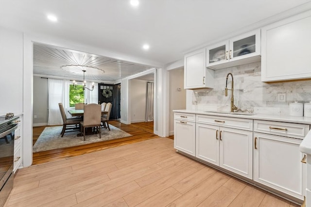 17 Atwood Ave, Millbury, MA 01527 - kitchen featuring a sink, light countertops, light wood-style flooring, white cabinetry, and tasteful backsplash