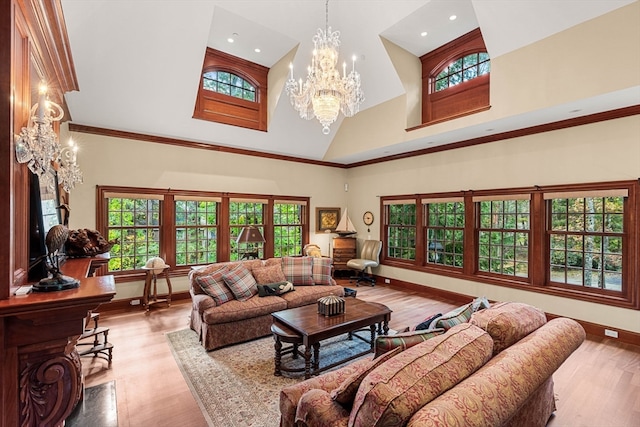 living room with light hardwood / wood-style floors, crown molding, a chandelier, and high vaulted ceiling