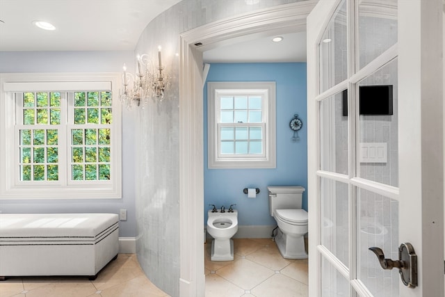 bathroom with tile patterned flooring, toilet, a bidet, and a wealth of natural light