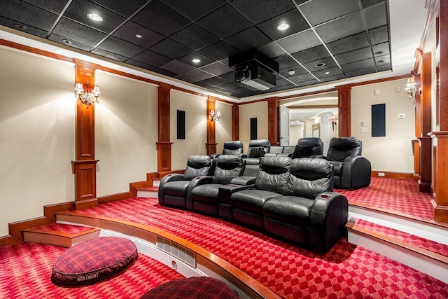 carpeted home theater with crown molding, a paneled ceiling, and decorative columns