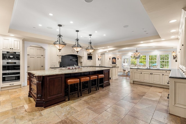 kitchen featuring a spacious island, decorative light fixtures, and a tray ceiling