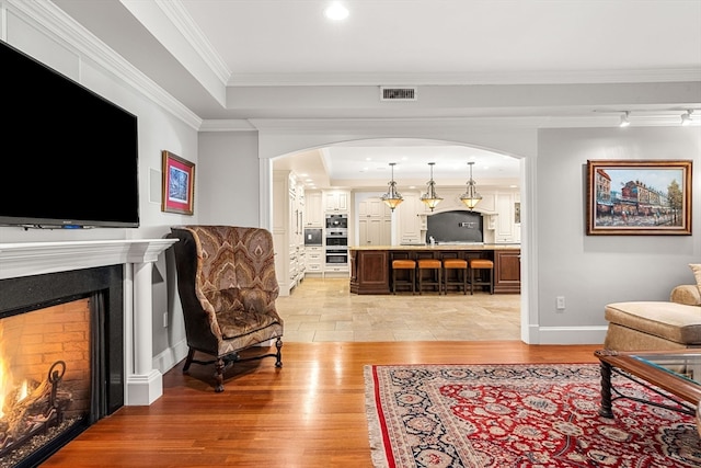 living room with light hardwood / wood-style floors, ornamental molding, and a tray ceiling