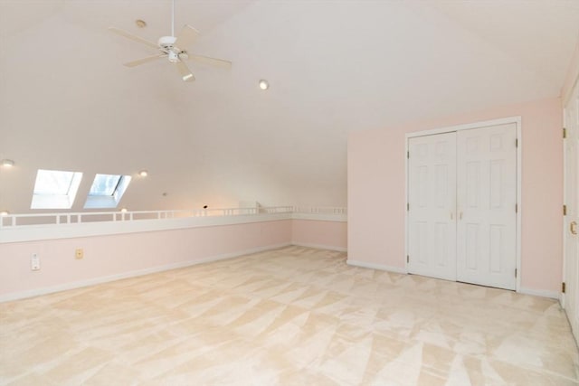 bonus room with lofted ceiling with skylight, light colored carpet, and ceiling fan