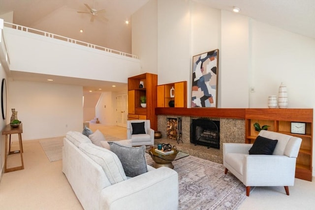 carpeted living room featuring a tiled fireplace, ceiling fan, and high vaulted ceiling