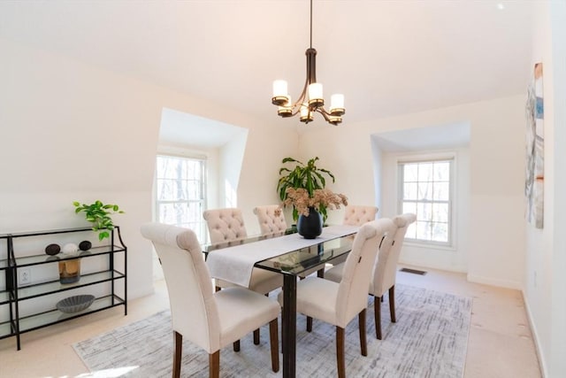 carpeted dining area featuring a wealth of natural light and an inviting chandelier