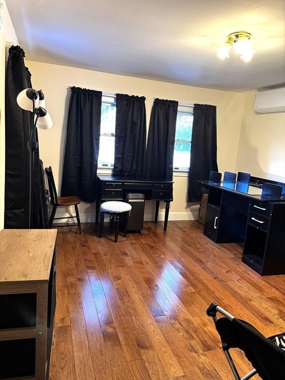 home office with an AC wall unit and hardwood / wood-style flooring