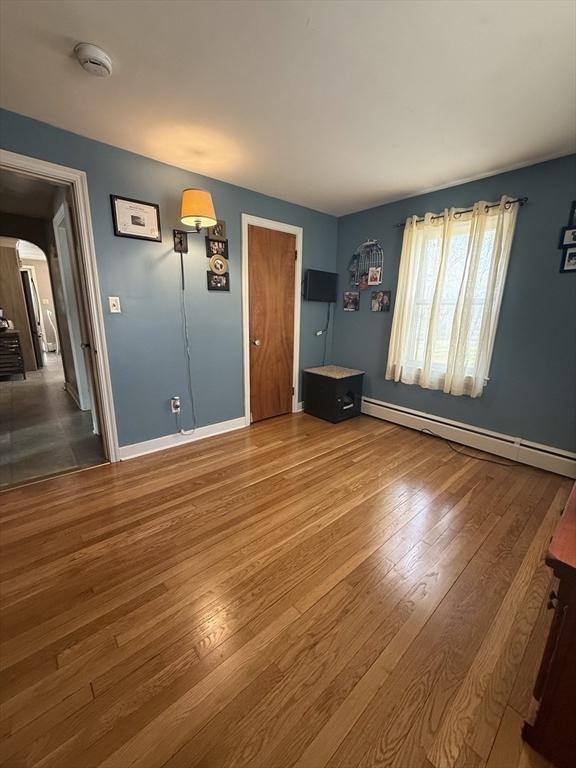 interior space with hardwood / wood-style flooring, arched walkways, baseboards, and baseboard heating