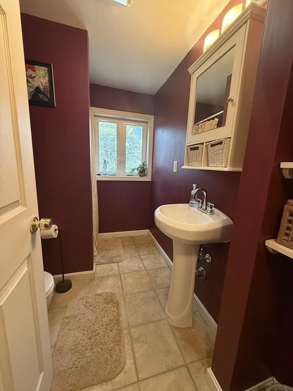 bathroom featuring toilet, baseboards, and a sink