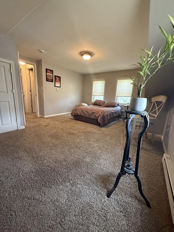 carpeted bedroom featuring baseboards and a baseboard radiator