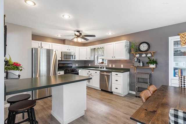 42 Guillotte St, Acushnet, MA 02743 - kitchen with appliances with stainless steel finishes, dark countertops, a ceiling fan, white cabinets, and light wood-style flooring