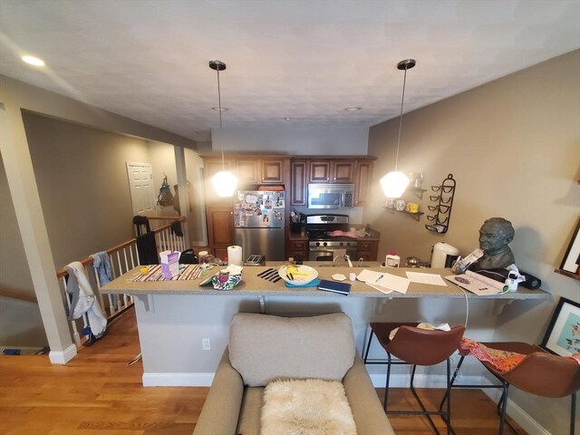 279-279A Dorchester St, Boston, MA 02127 - kitchen with appliances with stainless steel finishes, a kitchen breakfast bar, light wood-type flooring, pendant lighting, and a sink