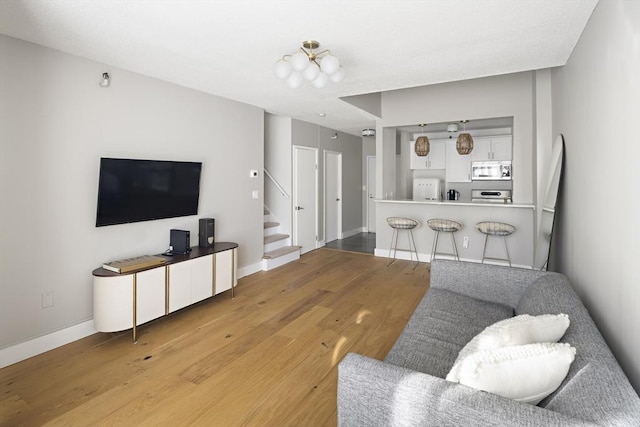 living area with stairs, baseboards, and light wood-style floors