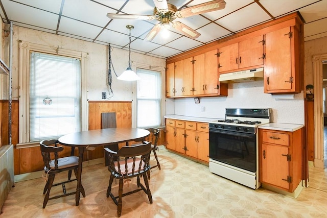kitchen featuring a ceiling fan, light floors, under cabinet range hood, light countertops, and gas range gas stove