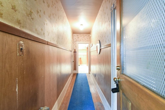 corridor featuring baseboards and wallpapered walls