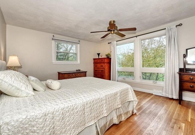 bedroom with light wood-type flooring, baseboards, and a ceiling fan