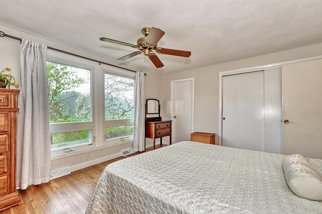 bedroom with baseboards, light wood finished floors, a closet, and a ceiling fan
