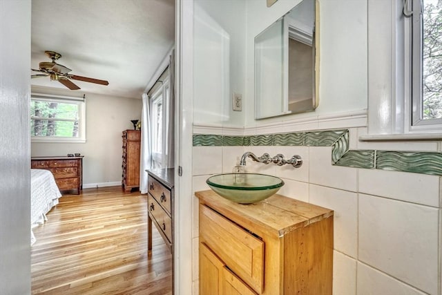 kitchen featuring a sink, light wood-style floors, a ceiling fan, butcher block counters, and baseboards