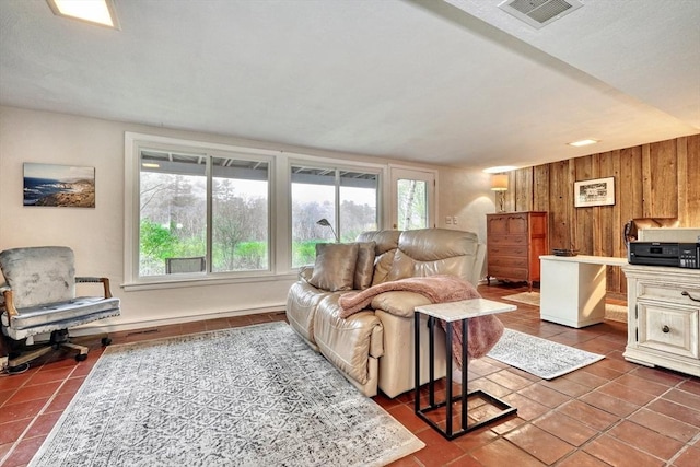 living area featuring dark tile patterned flooring, healthy amount of natural light, and wooden walls
