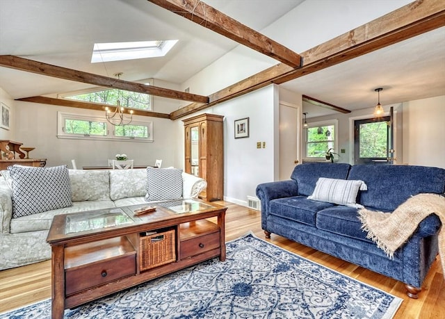 living area with a skylight, wood finished floors, a chandelier, and baseboards