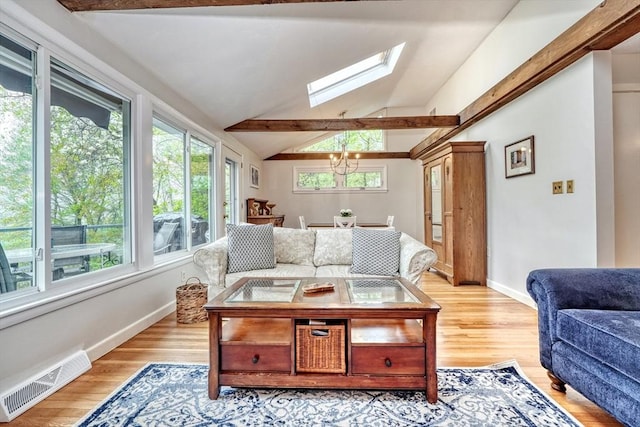 living area with a skylight, vaulted ceiling, baseboards, a chandelier, and light wood-style floors