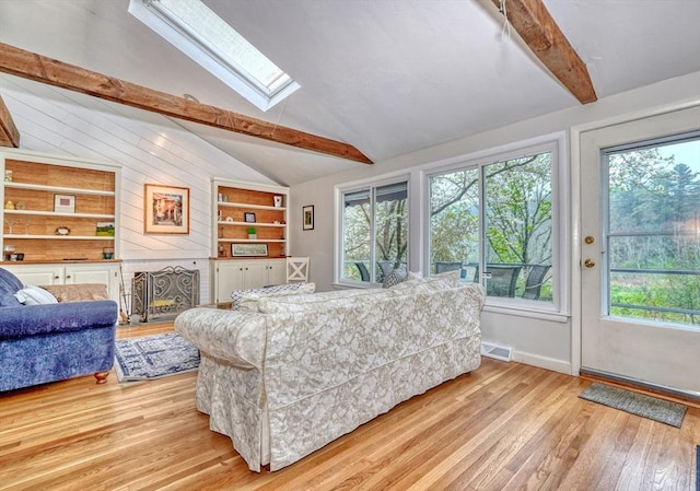 living room with a skylight, wood finished floors, built in shelves, and baseboards
