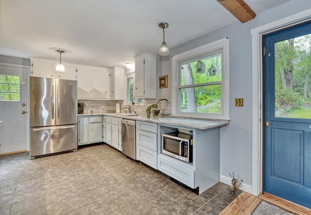 kitchen featuring appliances with stainless steel finishes, a sink, light countertops, and white cabinets