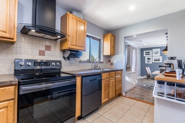 kitchen featuring backsplash, black appliances, wall chimney range hood, sink, and light wood-type flooring