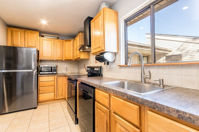 kitchen featuring sink, wall chimney range hood, tasteful backsplash, light tile patterned floors, and black appliances