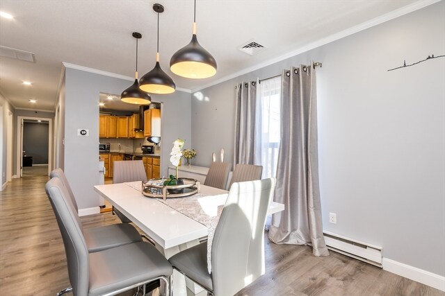 dining room with a baseboard heating unit, ornamental molding, and light hardwood / wood-style flooring