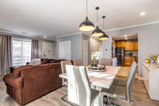 dining space featuring light hardwood / wood-style floors and crown molding