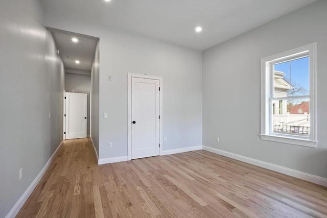 spare room with baseboards, light wood-type flooring, and recessed lighting