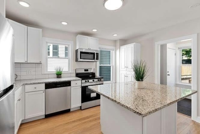 9 Foster St Unit 2, Gloucester, MA 01930 - kitchen featuring appliances with stainless steel finishes, plenty of natural light, white cabinets, light stone countertops, and recessed lighting