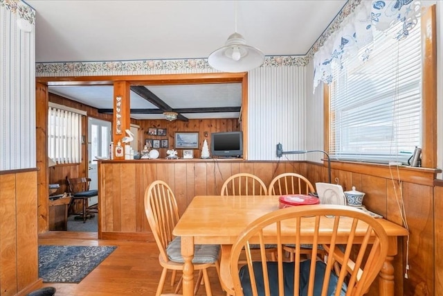 dining area with hardwood / wood-style floors, wood walls, and beam ceiling