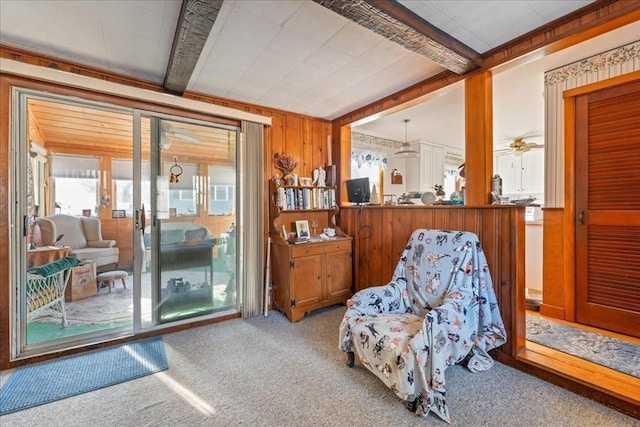 living area with beamed ceiling, carpet floors, and wood walls