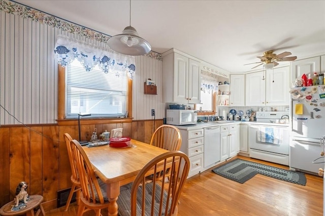 kitchen with ceiling fan, wooden walls, white cabinets, and white appliances