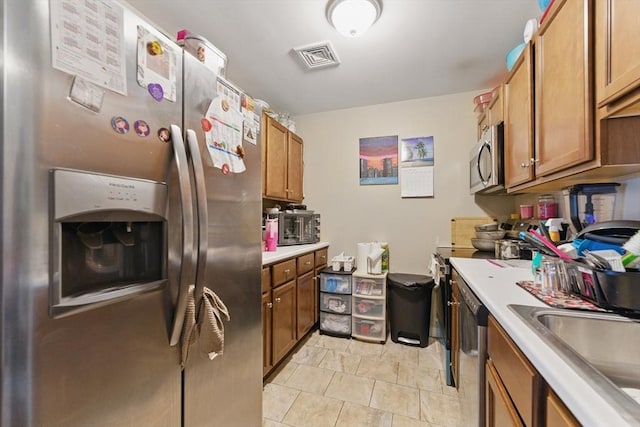 450 Somerset Ave Unit 3-6, Taunton, MA 02780 - kitchen with stainless steel appliances, brown cabinetry, light countertops, a sink, and light tile patterned flooring
