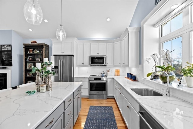 kitchen featuring pendant lighting, stainless steel appliances, gray cabinets, backsplash, and a sink