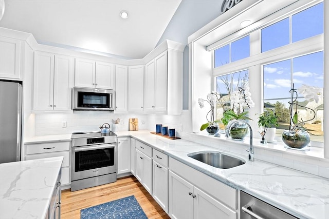 kitchen featuring light wood-style floors, appliances with stainless steel finishes, white cabinets, and a sink