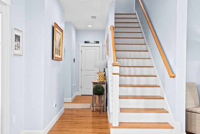 staircase featuring wood finished floors and baseboards