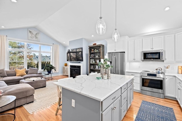 kitchen with a center island, stainless steel appliances, light wood-style floors, a glass covered fireplace, and open floor plan