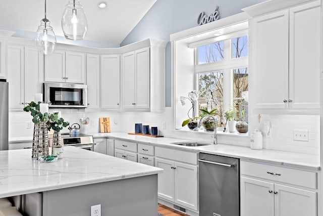 kitchen featuring white cabinetry, appliances with stainless steel finishes, vaulted ceiling, and a sink