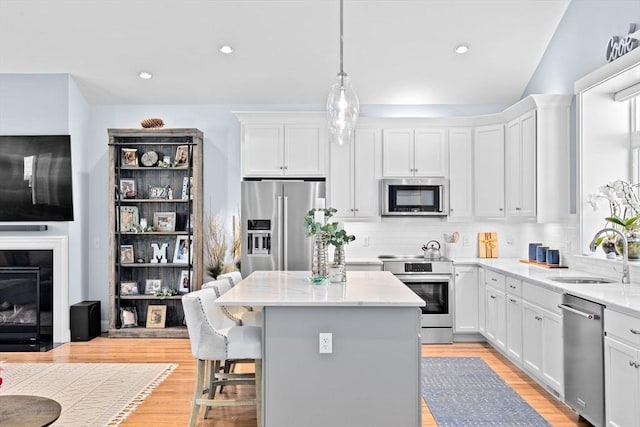 kitchen with white cabinets, stainless steel appliances, a sink, and a center island