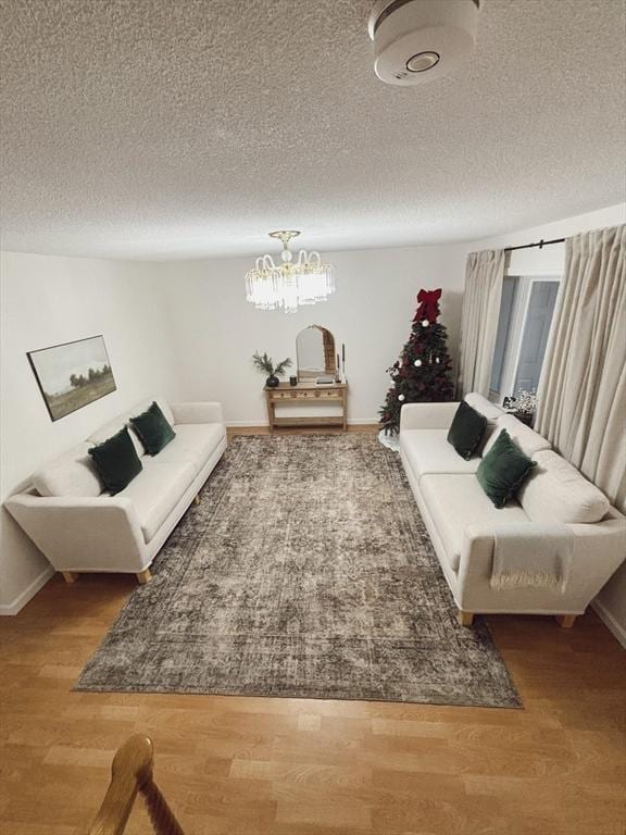 living room with wood-type flooring, a textured ceiling, and an inviting chandelier