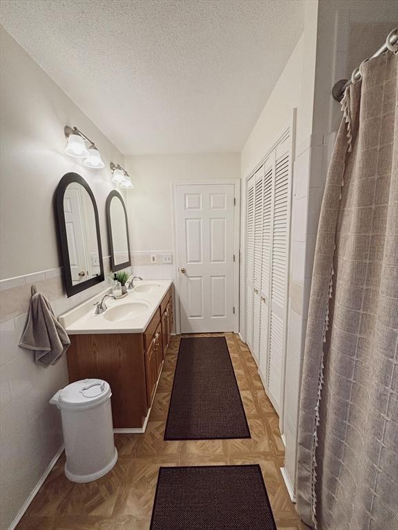 bathroom with parquet floors, curtained shower, vanity, and a textured ceiling